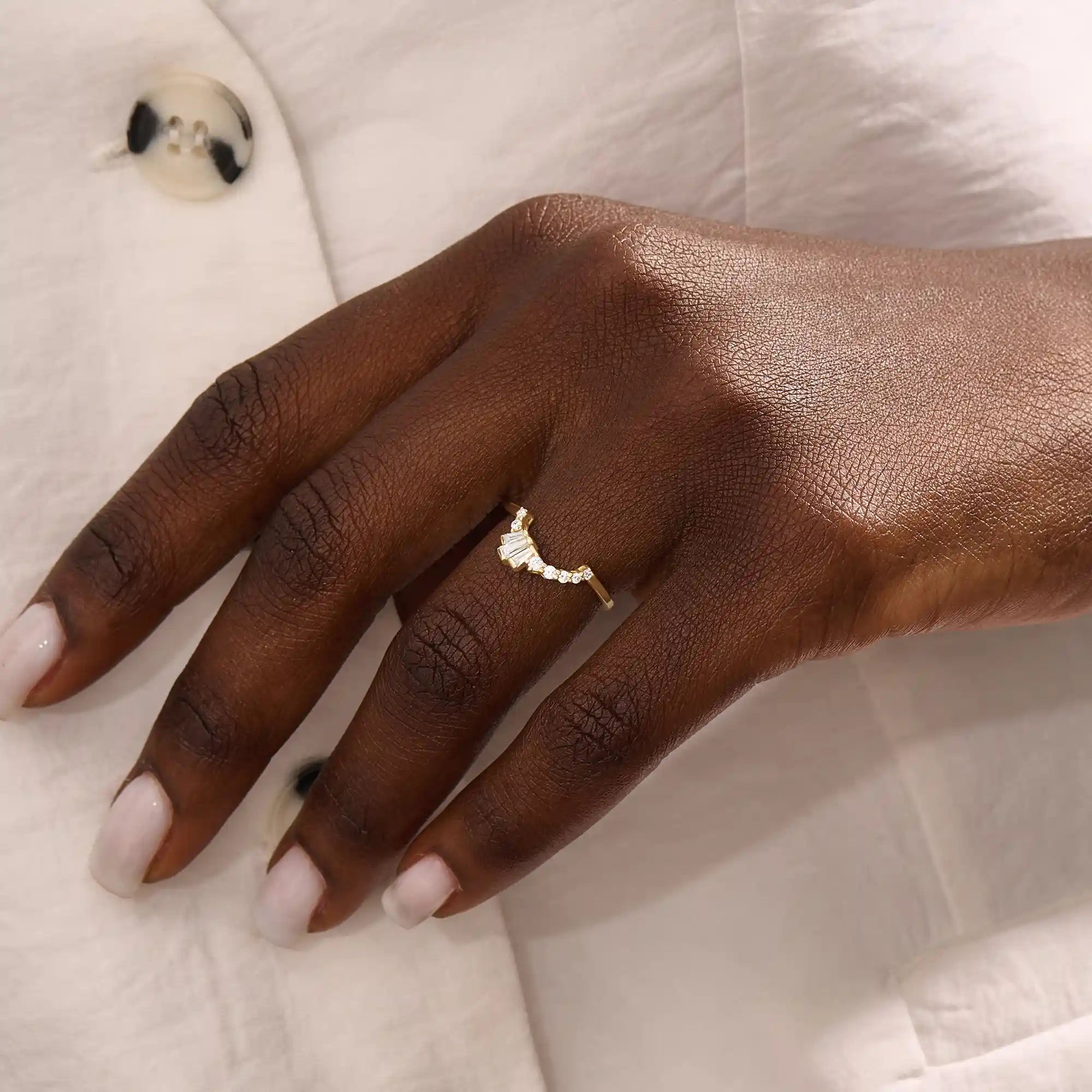 Model wears a curved gold ring adorned with baguette moissanites in an arch design. Sleek and contemporary, perfect for layering with solitaires.