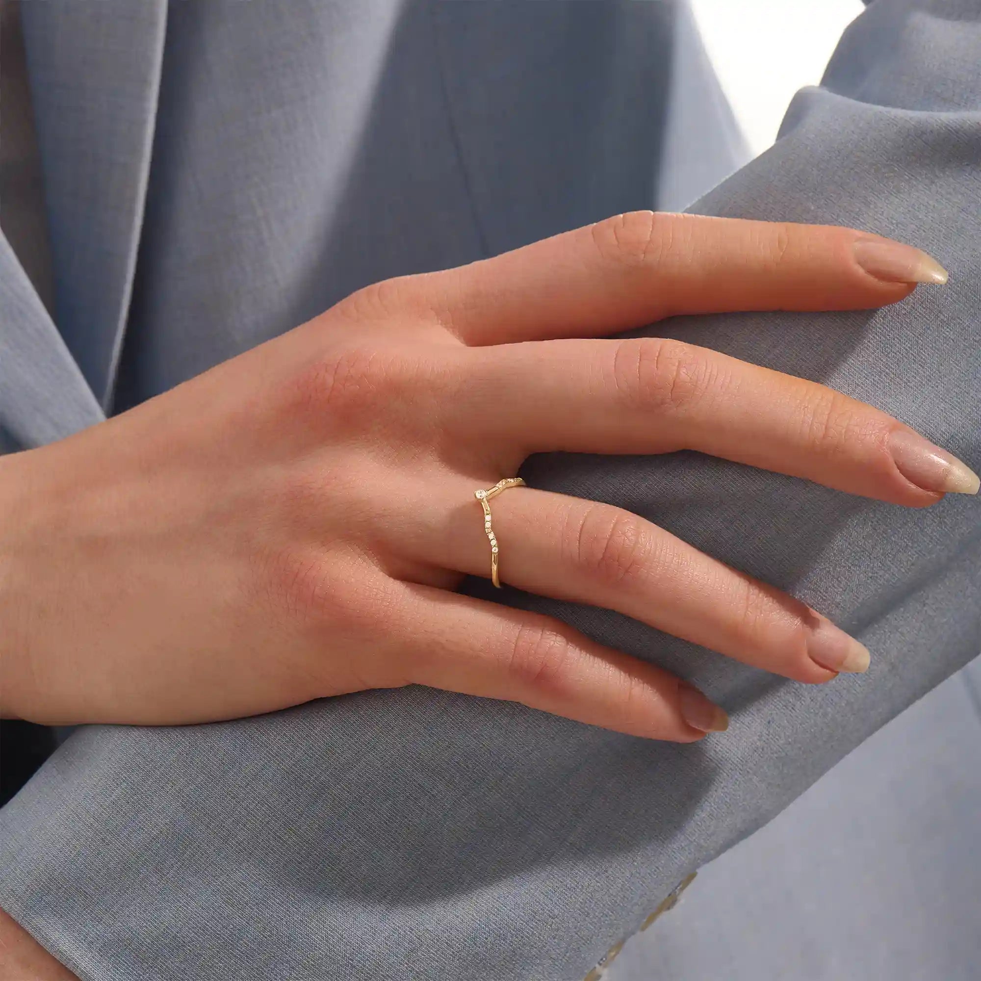 Model wears a dainty chevron curve ring with pavé moissanites in 14k gold. Ideal for stacking or pairing with a solitaire engagement ring.