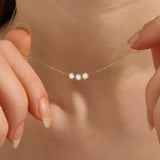 Model wears a delicate 14k gold necklace with three bezel-set moissanites. Elegant and versatile, ideal for stacking with other necklaces.