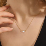 Model wears a delicate 14k gold necklace with three bezel-set moissanites. Elegant and versatile, ideal for stacking with other necklaces.