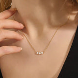 Model wears a delicate 14k gold necklace with three bezel-set moissanites. Elegant and versatile, ideal for stacking with other necklaces.