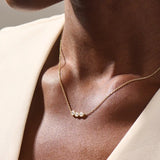 Model wears a delicate 14k gold necklace with three bezel-set moissanites. Elegant and versatile, ideal for stacking with other necklaces.