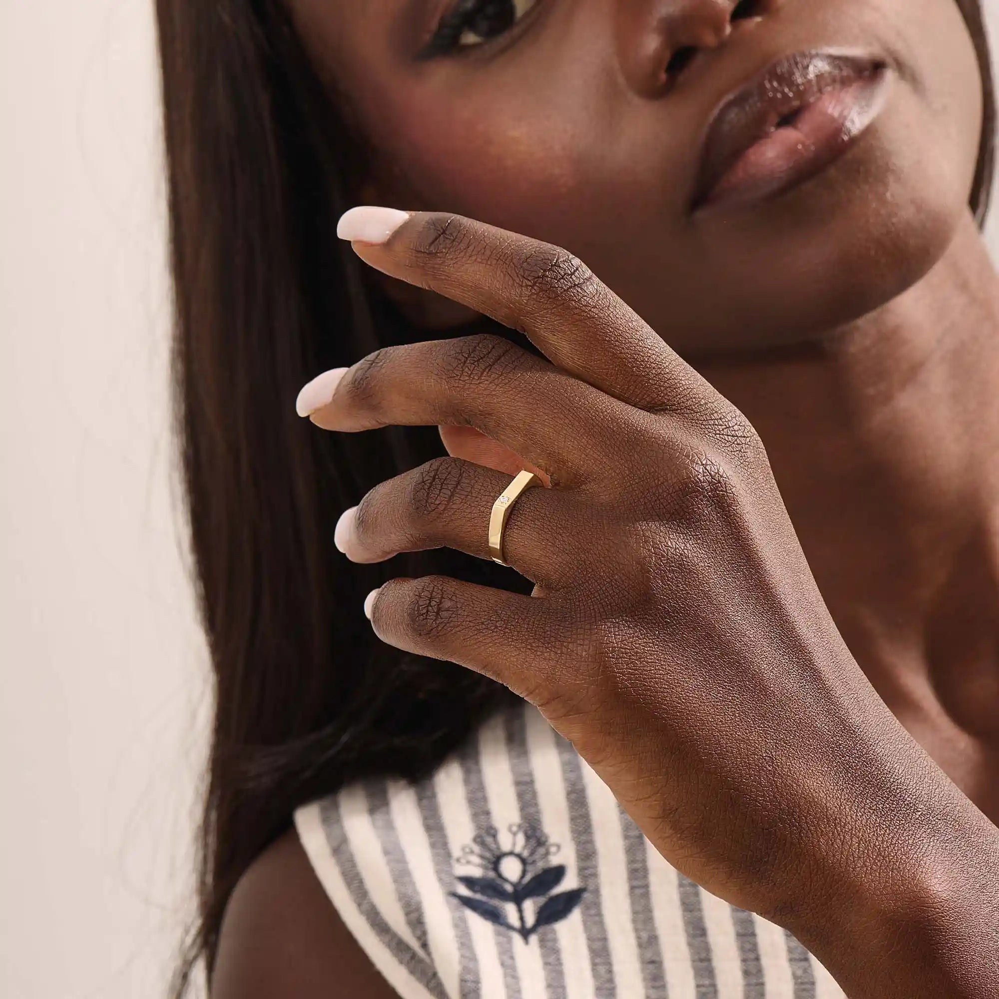 Model wears a simple 14k gold pinky signet ring with a solo moissanite accent. A contemporary and elegant piece for subtle statement style.