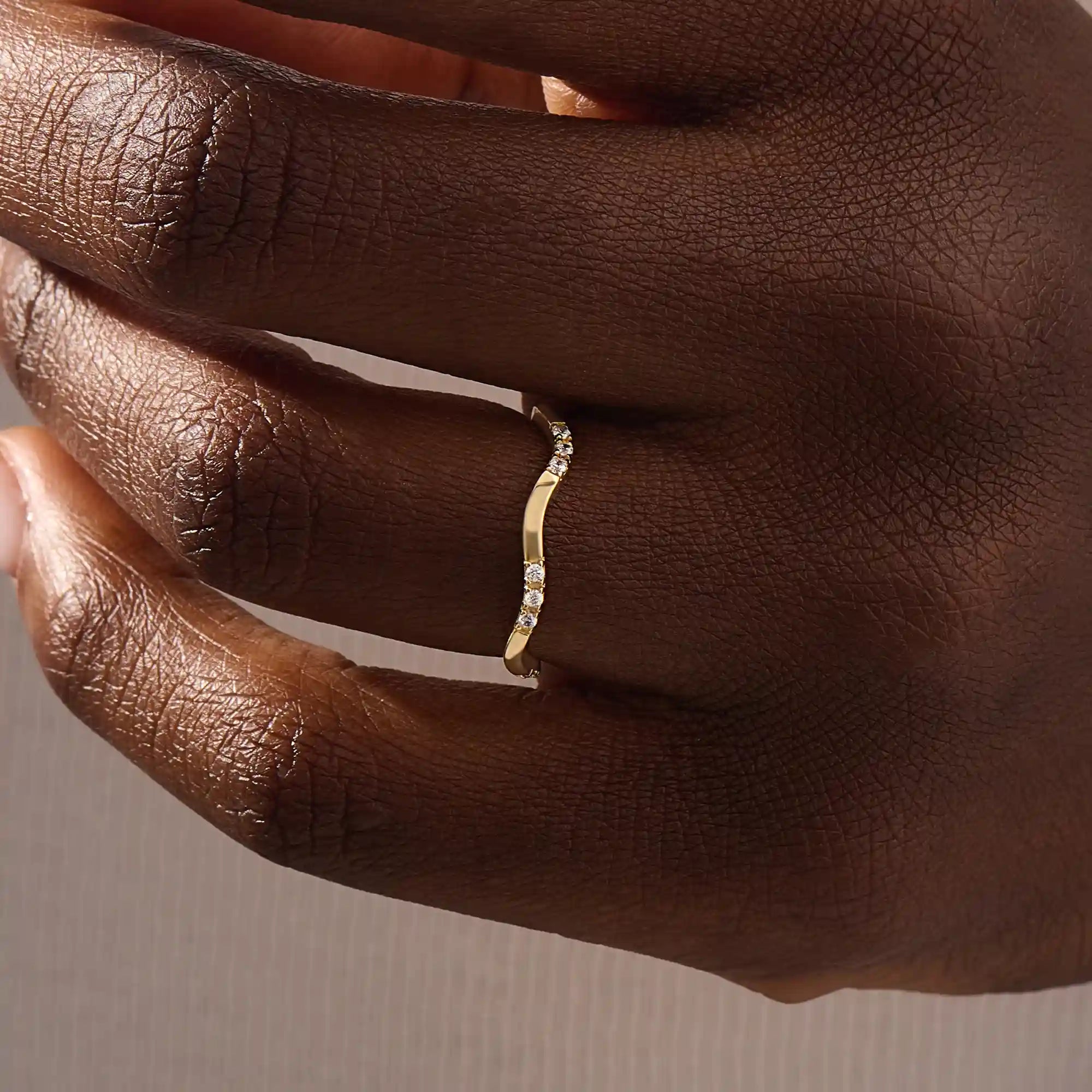Model wears a slim 14k gold curvy band ring adorned with small moissanites. Perfect for layering or wearing solo as a subtle statement.