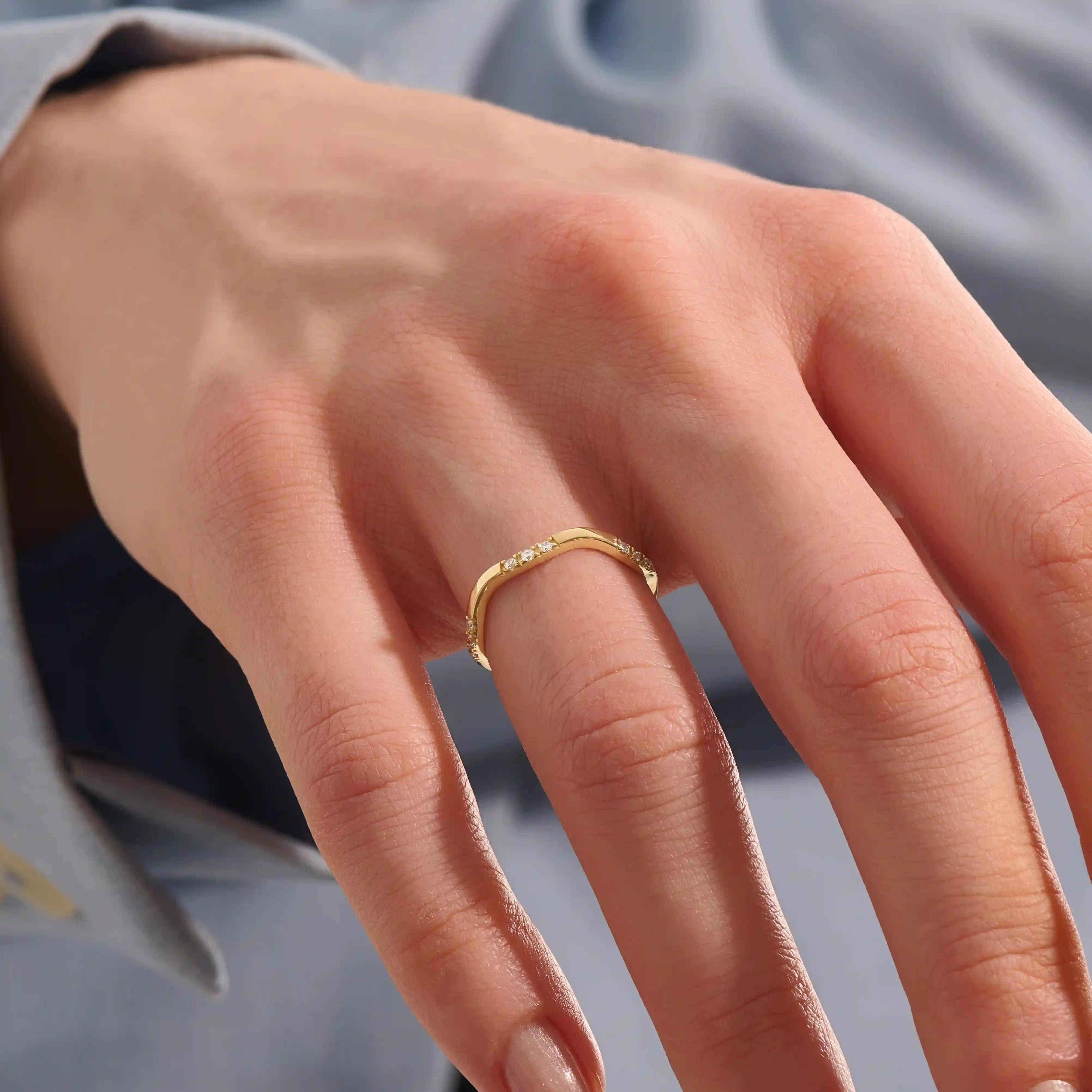 Model wears a slim 14k gold curvy band ring adorned with small moissanites. Perfect for layering or wearing solo as a subtle statement.