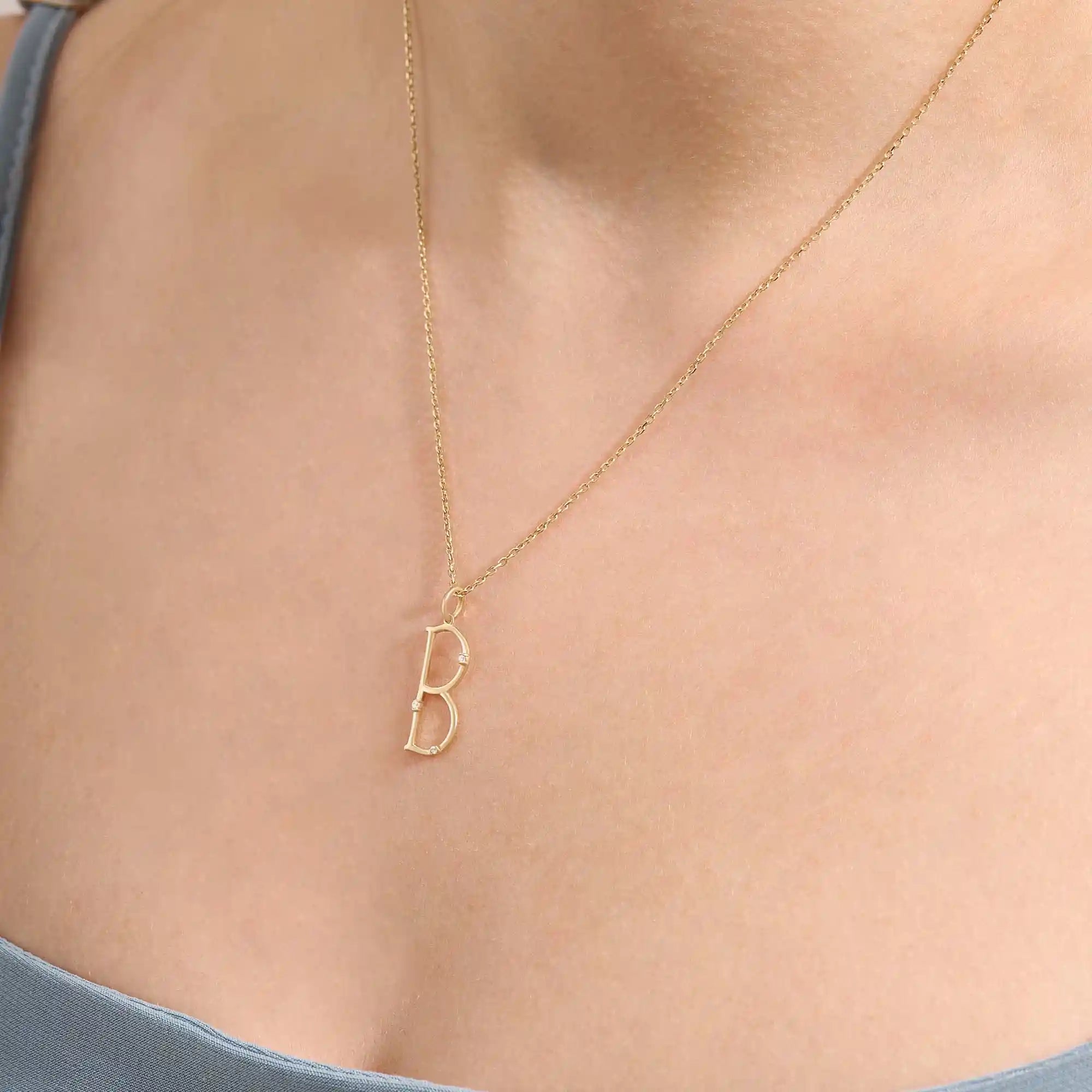 Model wears a slim 14k gold initial necklace featuring dainty moissanites. Elegant and minimal, perfect for layering or gifting.