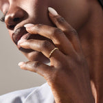 Model wears a slim 14k solid gold stacking ring adorned with delicate tiny flower motifs, perfect for layering with other rings.