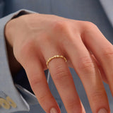 Model wears a slim 14k solid gold stacking ring adorned with delicate tiny flower motifs, perfect for layering with other rings.