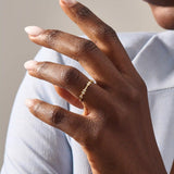 Model wears a slim 14k solid gold stacking ring adorned with delicate tiny flower motifs, perfect for layering with other rings.