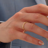 Model wears a slim 14k solid gold stacking ring adorned with delicate tiny flower motifs, perfect for layering with other rings.