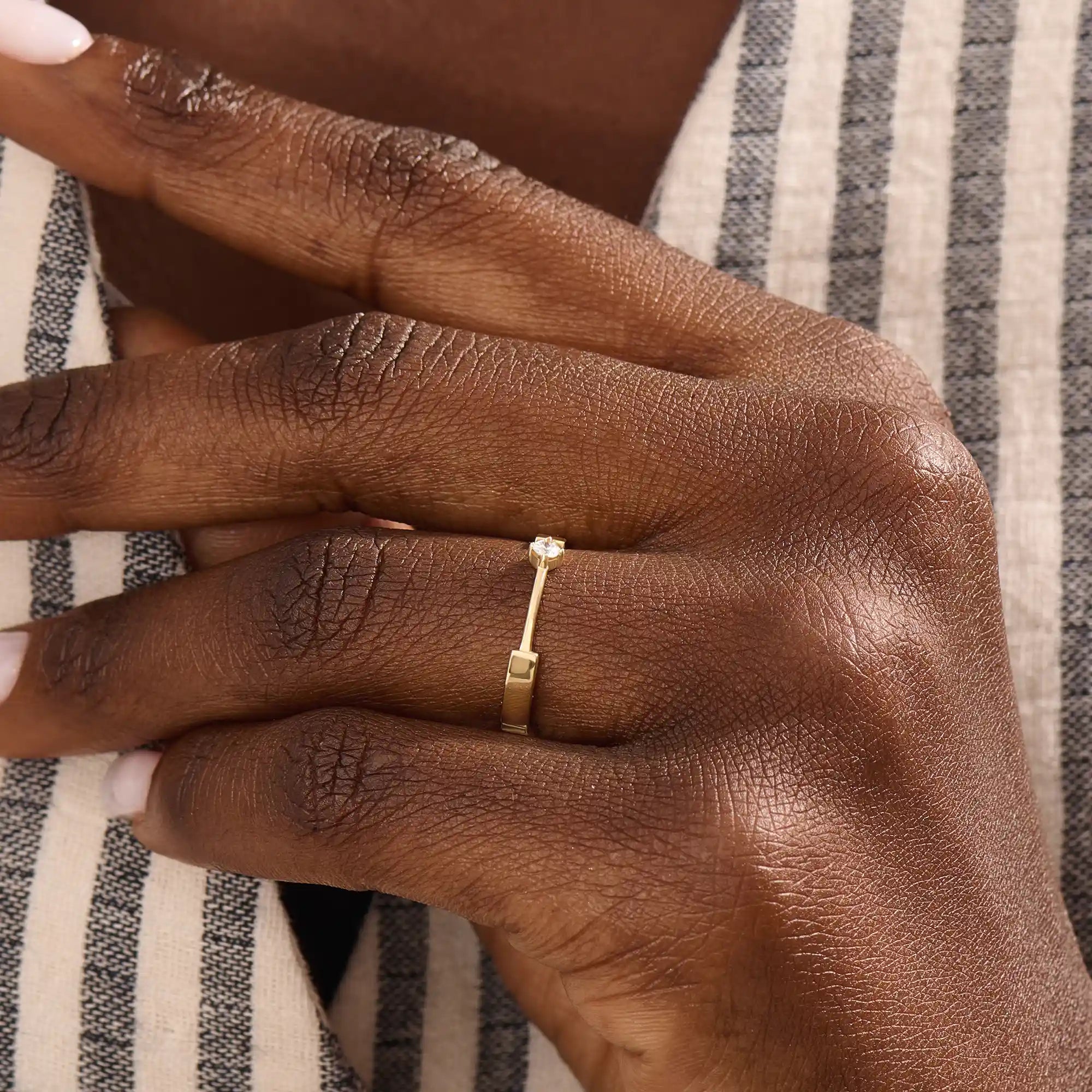 Model wears a uniquely designed 14k gold promise ring with a solo moissanite centerpiece. A stylish and meaningful symbol of commitment.