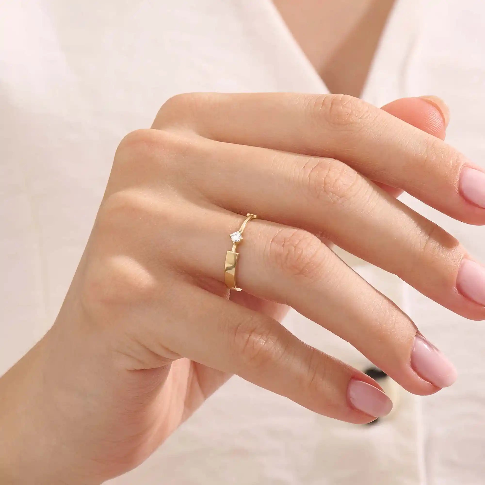 Model wears a uniquely designed 14k gold promise ring with a solo moissanite centerpiece. A stylish and meaningful symbol of commitment.