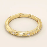 Side angle view of a 14k solid yellow gold bamboo-inspired wedding band with round brilliant-cut moissanites in a spaced setting