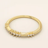 Side angle view of a 14k solid yellow gold band with round brilliant cut moissanite stones in alternating prong and bead settings, elegant stacking or wedding ring