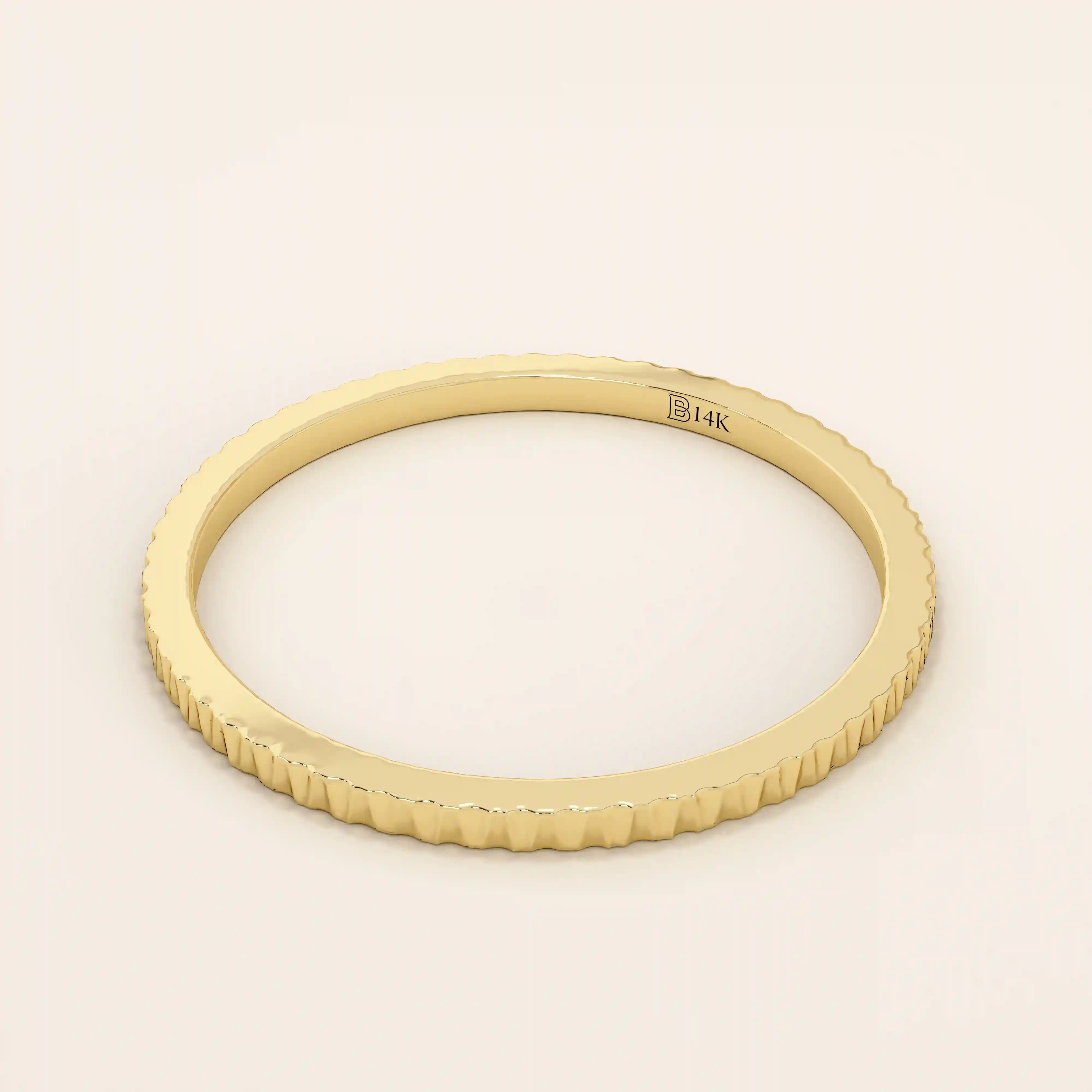 Side angle view of a 14k solid yellow gold thin stacking ring with faceted textured design, simple and modern fine jewelry for layering
