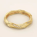 Side angle view of a 14k solid yellow gold twist eternity wedding band with rows of sparkling moissanites in an elegant sculpted design