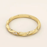 Side angle view of a 14k solid yellow gold twisted wedding band with a cluster of round brilliant moissanites in a marquise-shaped opening, sleek and contemporary design