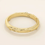 Side angle view of a 14k solid yellow gold wedding band with woodgrain-inspired detailing, nature-inspired craftsmanship