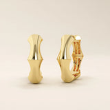 Side profile view of 14k solid yellow gold bone hoop earrings, showcasing their contoured silhouette and smooth high-polish shine.