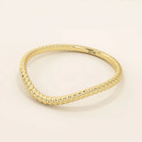 Slim curved stacking ring in 14k solid gold with a delicate twisted band. Designed to nest with engagement rings or wear alone for subtle texture.