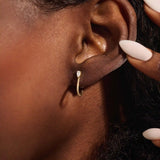 Woman wearing 14k solid gold U-shaped stud earrings with pear moissanites at the front. Bold yet minimal gold studs for everyday style. Great for adding a touch of sparkle.
