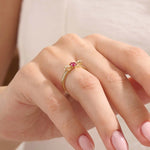 Woman wearing a 14k gold ribbon-inspired ruby ring. Feminine and unique gemstone ring perfect for meaningful gifts or daily wear.