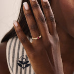 Woman wearing a 14k gold ribbon-inspired ruby ring. Feminine and unique gemstone ring perfect for meaningful gifts or daily wear.
