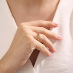 Woman wearing a 14k gold ribbon-inspired ruby ring. Feminine and unique gemstone ring perfect for meaningful gifts or daily wear.