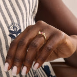 Woman wearing a 14k gold ribbon-inspired ruby ring. Feminine and unique gemstone ring perfect for meaningful gifts or daily wear.