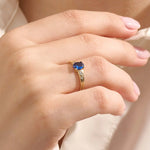 Woman wearing a 14k gold ring with a deep blue oval sapphire. A refined and classic gemstone ring, ideal as a gift or statement piece.