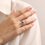 Woman wearing a 14k gold ring with a deep blue oval sapphire. A refined and classic gemstone ring, ideal as a gift or statement piece.