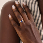 Woman wearing a 14k gold ring with a deep blue oval sapphire. A refined and classic gemstone ring, ideal as a gift or statement piece.