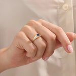 Woman wearing a 14k gold signet ring featuring a bezel set sapphire. Sleek and elegant for everyday wear. A timeless gemstone ring with personal charm.