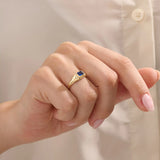 Woman wearing a 14k gold signet ring featuring a bezel set sapphire. Sleek and elegant for everyday wear. A timeless gemstone ring with personal charm.