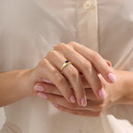 Woman wearing a 14k gold signet ring featuring a bezel set sapphire. Sleek and elegant for everyday wear. A timeless gemstone ring with personal charm.