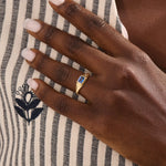 Woman wearing a 14k gold signet ring featuring a bezel set sapphire. Sleek and elegant for everyday wear. A timeless gemstone ring with personal charm.