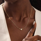 Woman wearing a 14k solid gold V-shaped necklace featuring a marquise moissanite in the middle. Chic minimalist gold jewelry. Perfect for layering or solo styling.