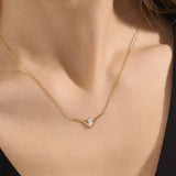 Woman wearing a 14k solid gold V-shaped necklace featuring a marquise moissanite in the middle. Chic minimalist gold jewelry. Perfect for layering or solo styling.