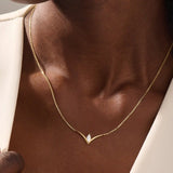 Woman wearing a 14k solid gold V-shaped necklace featuring a marquise moissanite in the middle. Chic minimalist gold jewelry. Perfect for layering or solo styling.