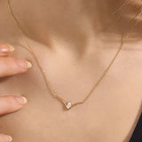 Woman wearing a 14k solid gold V-shaped necklace featuring a marquise moissanite in the middle. Chic minimalist gold jewelry. Perfect for layering or solo styling.