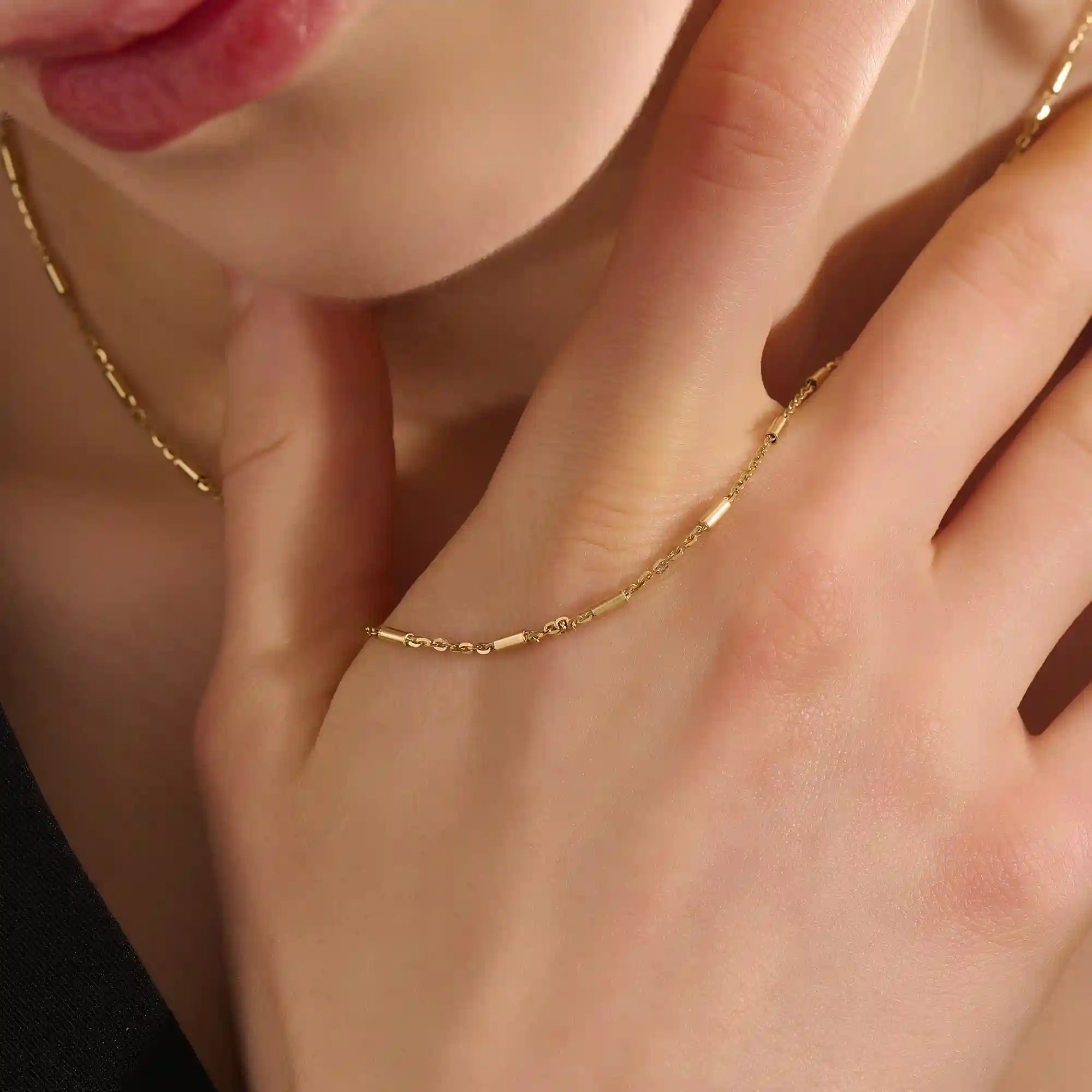 Woman wearing a 14k solid gold bar chain necklace with clean, linear links. A contemporary and elegant gold piece. Perfect for daily wear or stacking.