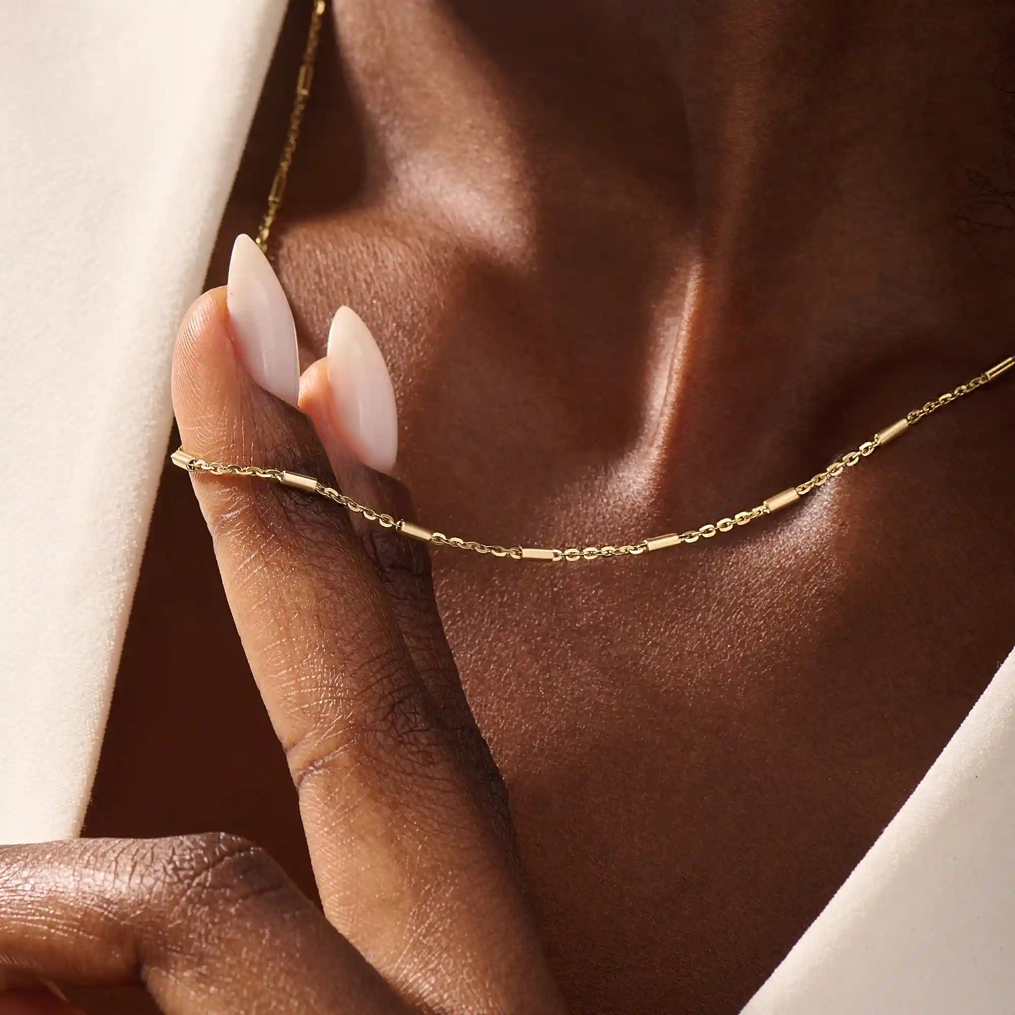 Woman wearing a 14k solid gold bar chain necklace with clean, linear links. A contemporary and elegant gold piece. Perfect for daily wear or stacking.