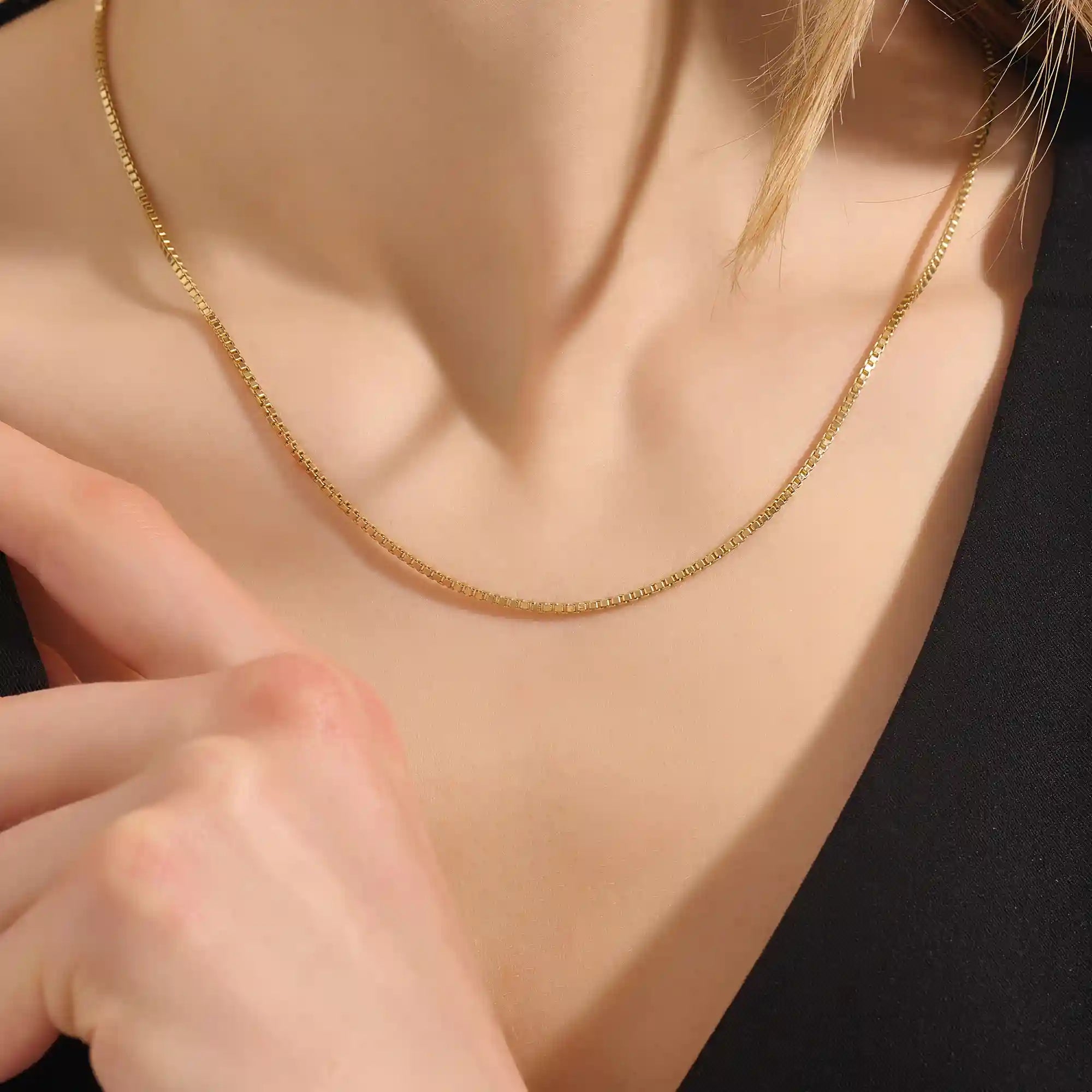 Woman wearing a 14k solid gold box chain necklace with sleek, structured links. Minimalist and versatile gold chain for everyday styling. Perfect on its own or with other pieces.