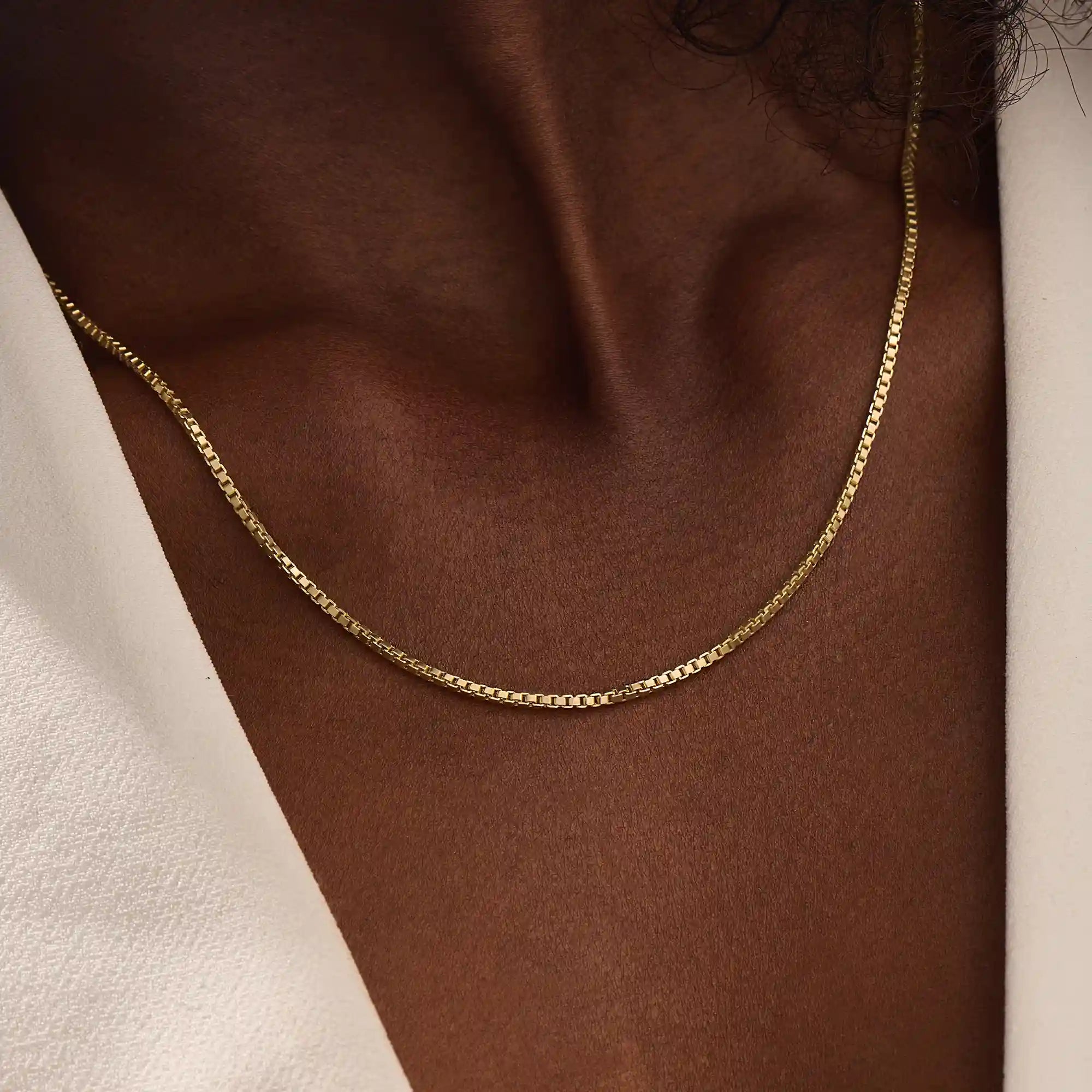 Woman wearing a 14k solid gold box chain necklace with sleek, structured links. Minimalist and versatile gold chain for everyday styling. Perfect on its own or with other pieces.