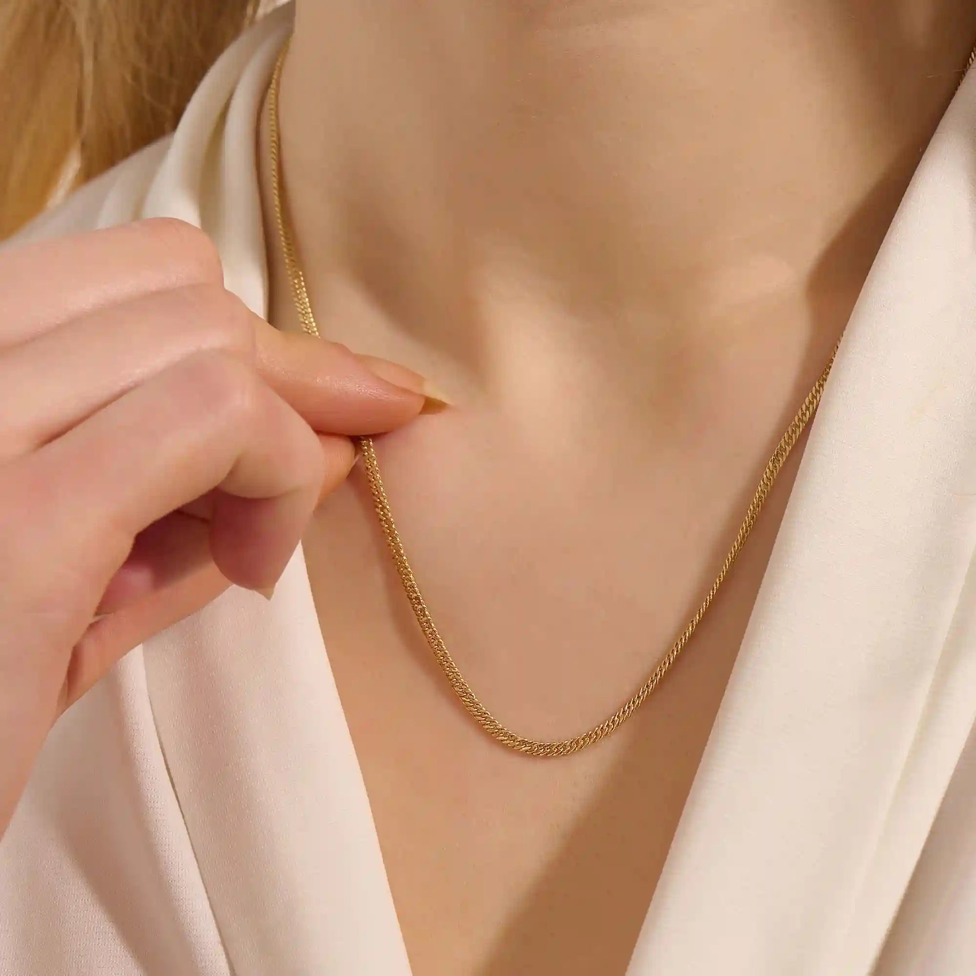 Woman wearing a 14k solid gold curb chain necklace with smooth, flat links that catch the light. A bold yet classic piece for daily styling. Perfect worn solo or stacked.