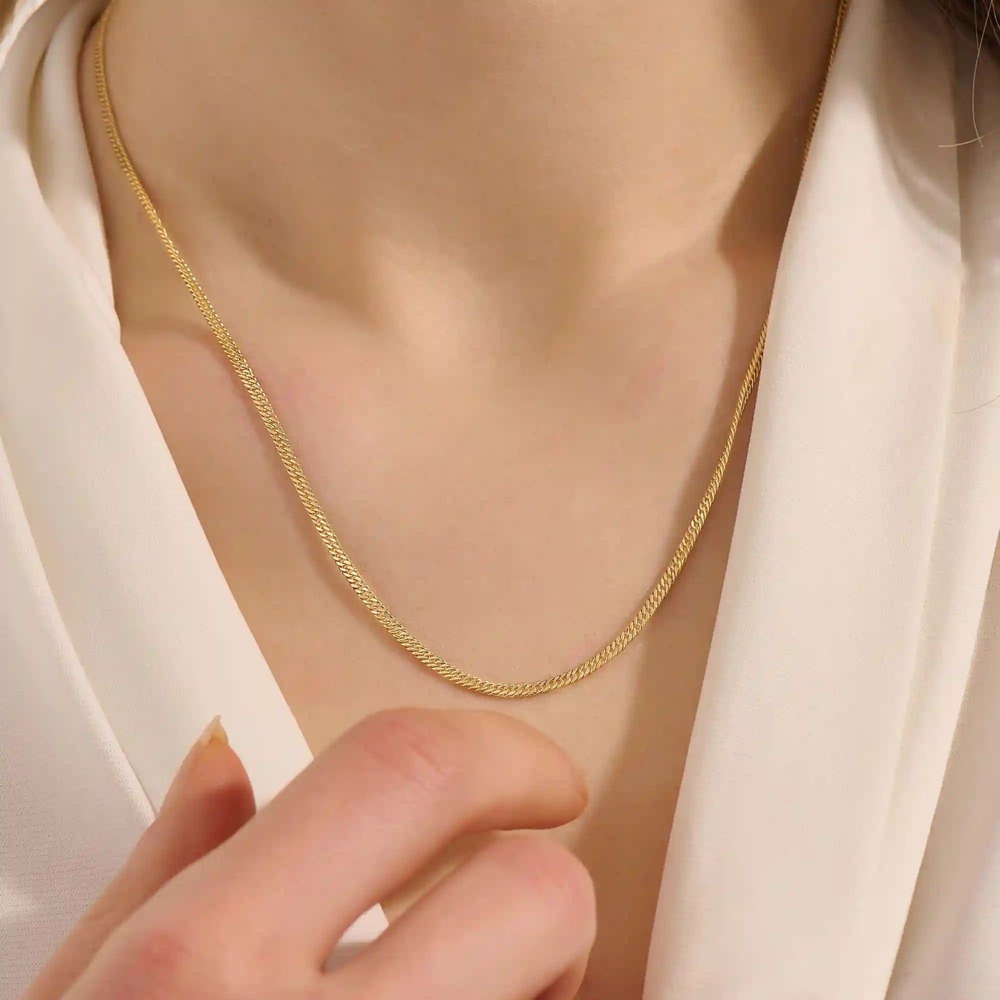 Woman wearing a 14k solid gold curb chain necklace with smooth, flat links that catch the light. A bold yet classic piece for daily styling. Perfect worn solo or stacked.