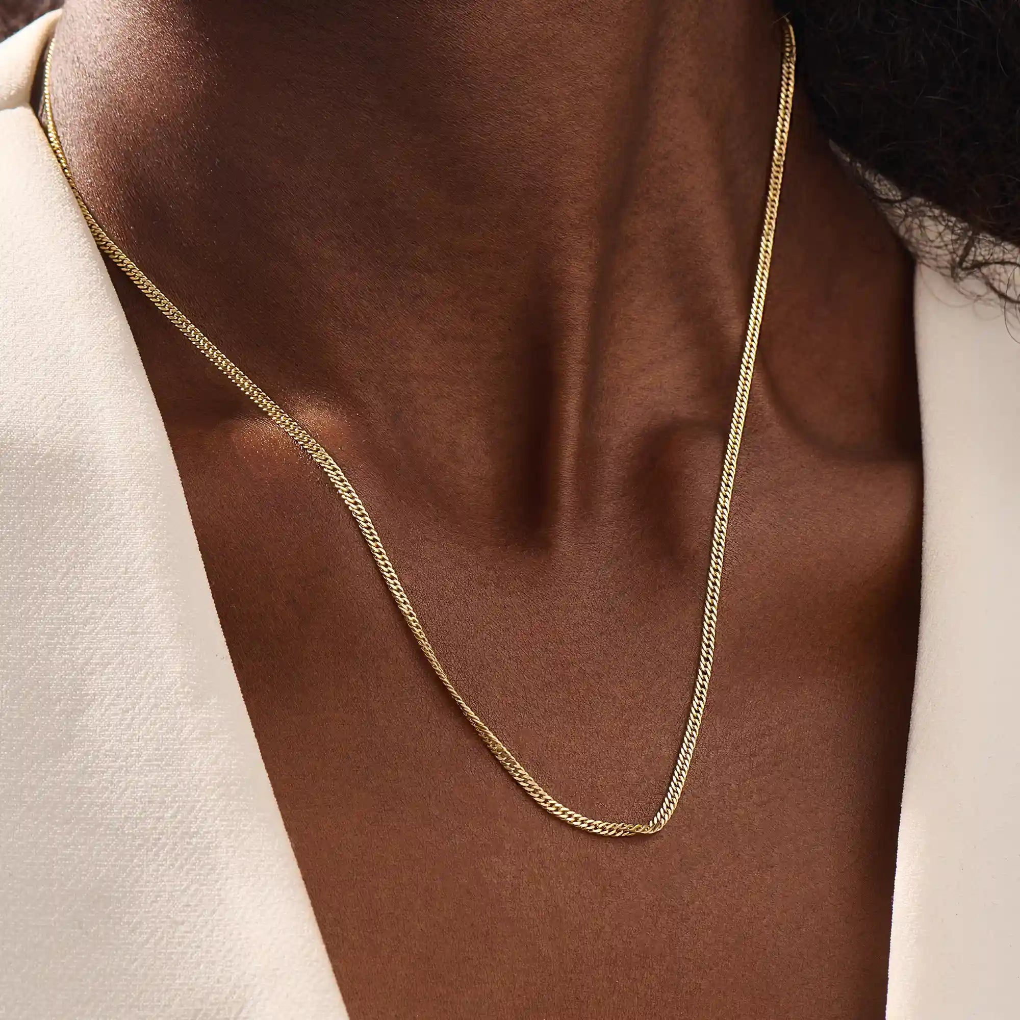 Woman wearing a 14k solid gold curb chain necklace with smooth, flat links that catch the light. A bold yet classic piece for daily styling. Perfect worn solo or stacked.