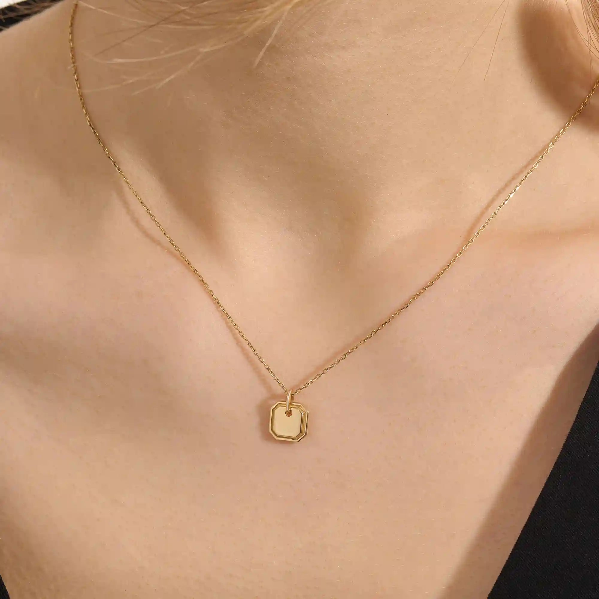 Woman wearing a 14k solid gold dainty octagon pendant necklace. Lightweight and easy-to-style gold charm. Perfect for daily looks or as a layering piece.