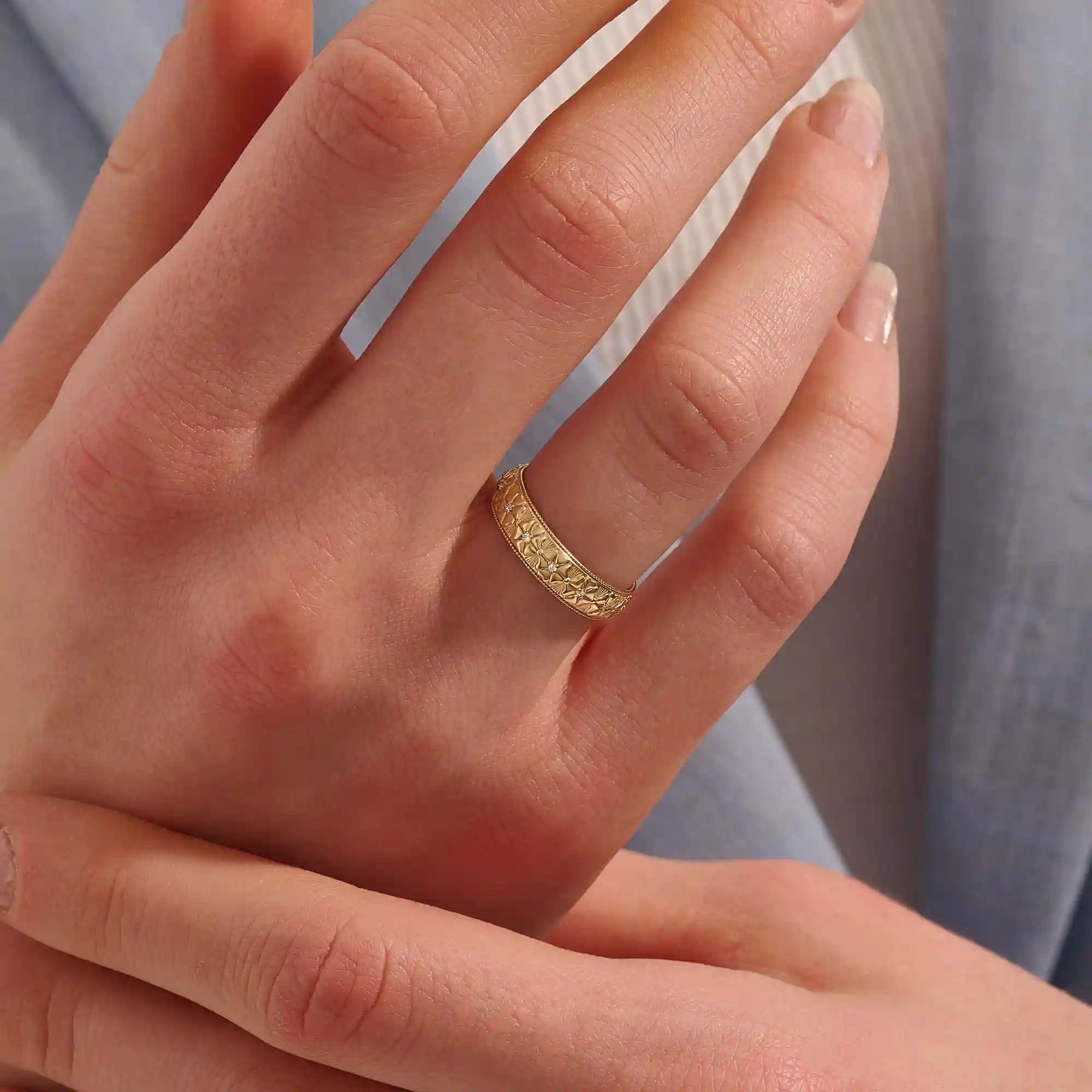 Woman wearing a 14k solid gold flower wedding band with raised floral details. A soft and timeless design for everyday use. Ideal as a meaningful or alternative wedding ring.