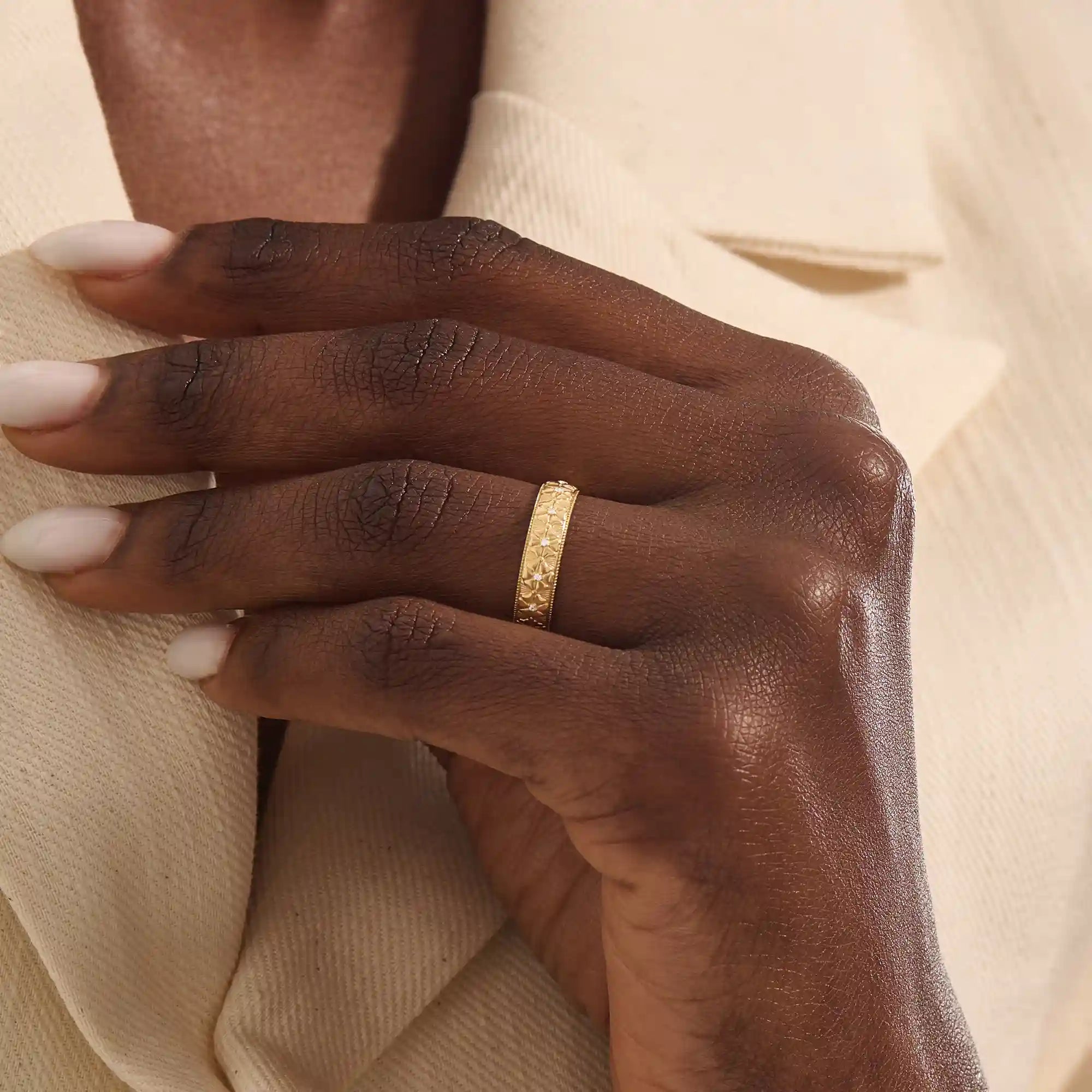 Woman wearing a 14k solid gold flower wedding band with raised floral details. A soft and timeless design for everyday use. Ideal as a meaningful or alternative wedding ring.
